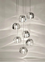 A cluster of clear crystal ball pendant lights hanging in a cascade, casting light patterns on the wall.