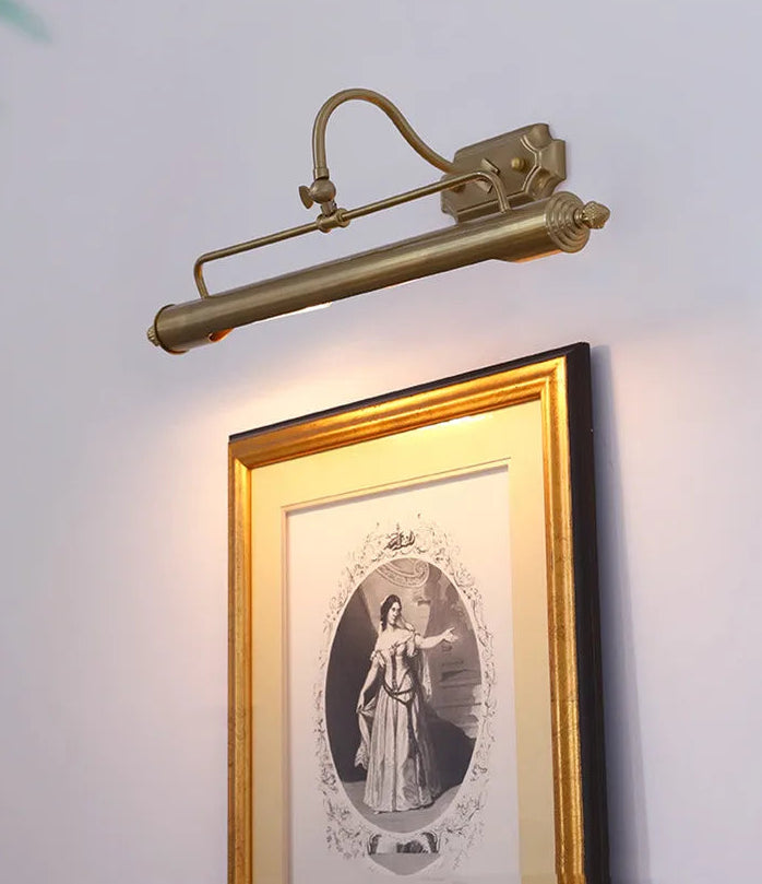 Brass wall light fixture above a framed picture on a white wall