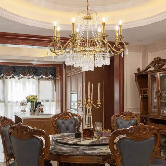 Brass tiered chandelier with cascading crystals hanging over a marble dining table.
