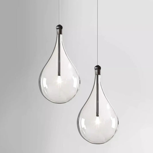 Two clear glass teardrop pendant lights hanging against a white background.