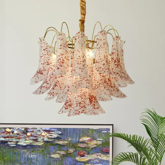 Close-up of a gold chandelier featuring bell-shaped glass shades with red speckles, showcasing the intricate design.