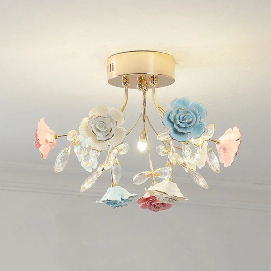 A flush mount ceiling light with a gold base, adorned with multi-colored ceramic roses and clear crystals.