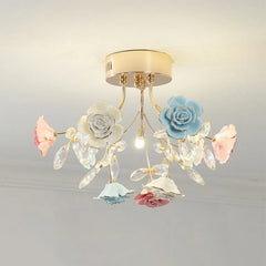A flush mount ceiling light with a gold base, adorned with multi-colored ceramic roses and clear crystals.