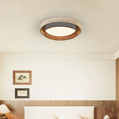 A bedroom ceiling with a decorative stone-textured ring flush mount light providing illumination.