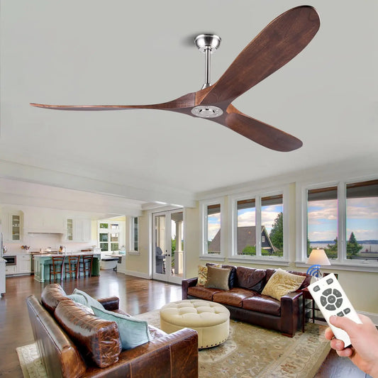 Brown wooden three-blade ceiling fan with a brushed nickel mount, shown in a living room with leather sofas and a remote control in hand.