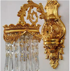 Side view of a golden wall sconce, showing the ornate backplate and the cascading crystal shades.