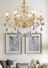 Gold chandelier hanging above a living room with framed pictures and decor.