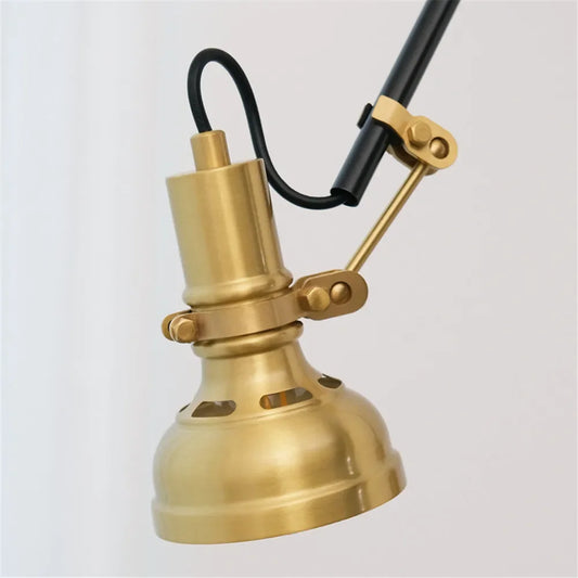 Close-up of the brass lamp head and adjustable arm mechanism of the wall sconce.