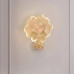Close-up view of a gold flower-shaped wall sconce, highlighting the textured glass and illuminated petals.