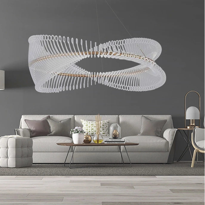 Modern living room with a white sofa, coffee table, and decorative items, featuring a large white chandelier.