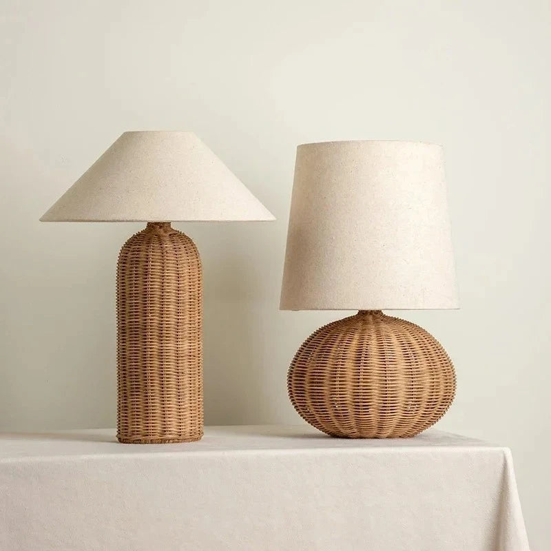 Two table lamps with woven rattan bases and fabric shades on a white tablecloth.