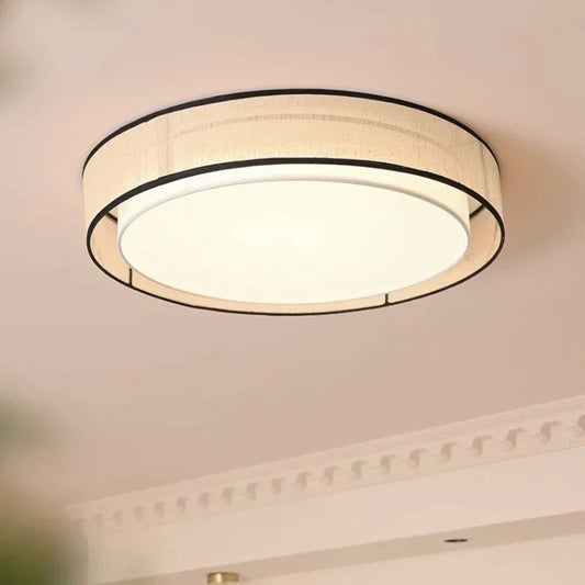 A room interior showing the beige fabric drum flush mount ceiling light installed on a white ceiling.