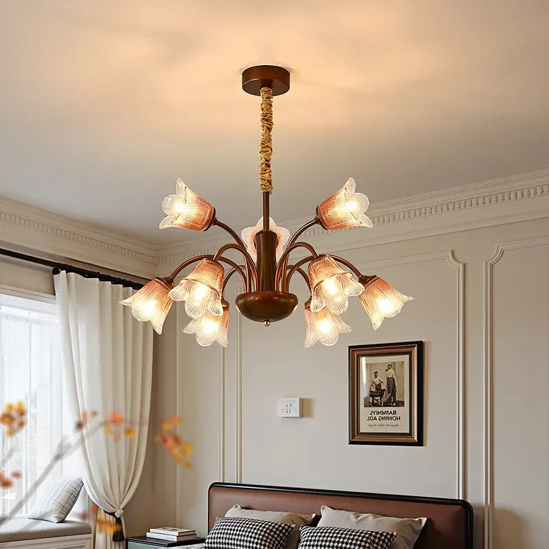 Bronze floral bud chandelier pendant light installed above a bed in a bedroom.