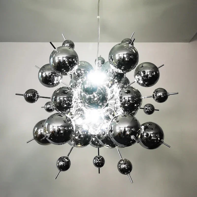 A chrome starburst chandelier with a metallic, atomic-like structure, made up of many reflective spheres and thin rods.