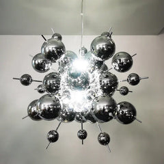 A chrome starburst chandelier with a metallic, atomic-like structure, made up of many reflective spheres and thin rods.