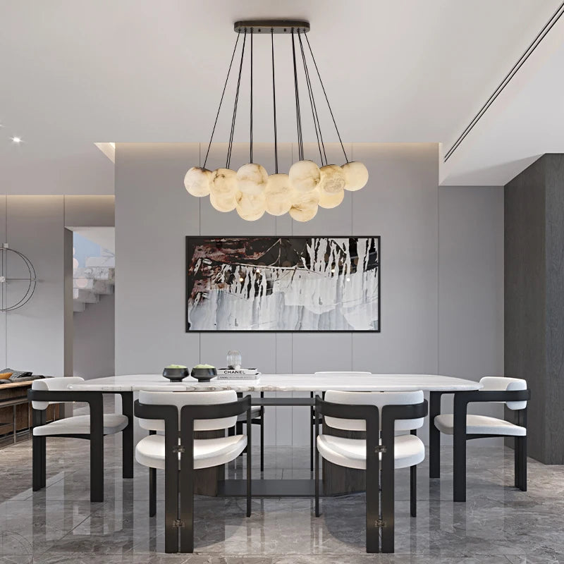 A dining room with a gold chandelier with marble-effect globes hanging over a table.