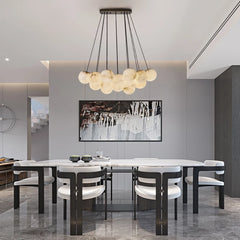 A dining room with a gold chandelier with marble-effect globes hanging over a table.