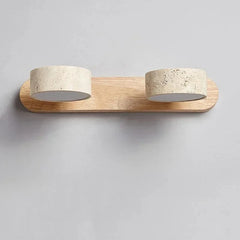 A wall sconce with a light wood base and two stone cylinder shades, presented against a plain gray background.