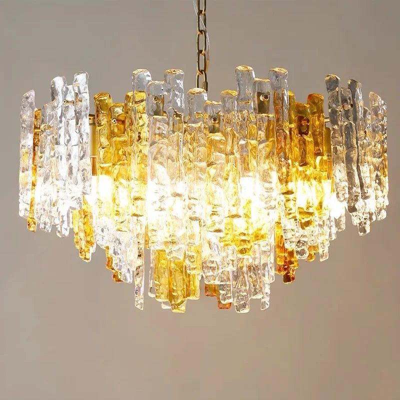 Detailed view of a glass tube chandelier displaying a dense arrangement of amber and clear glass rods, with warm light emanating from within.