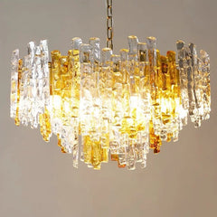Detailed view of a glass tube chandelier displaying a dense arrangement of amber and clear glass rods, with warm light emanating from within.