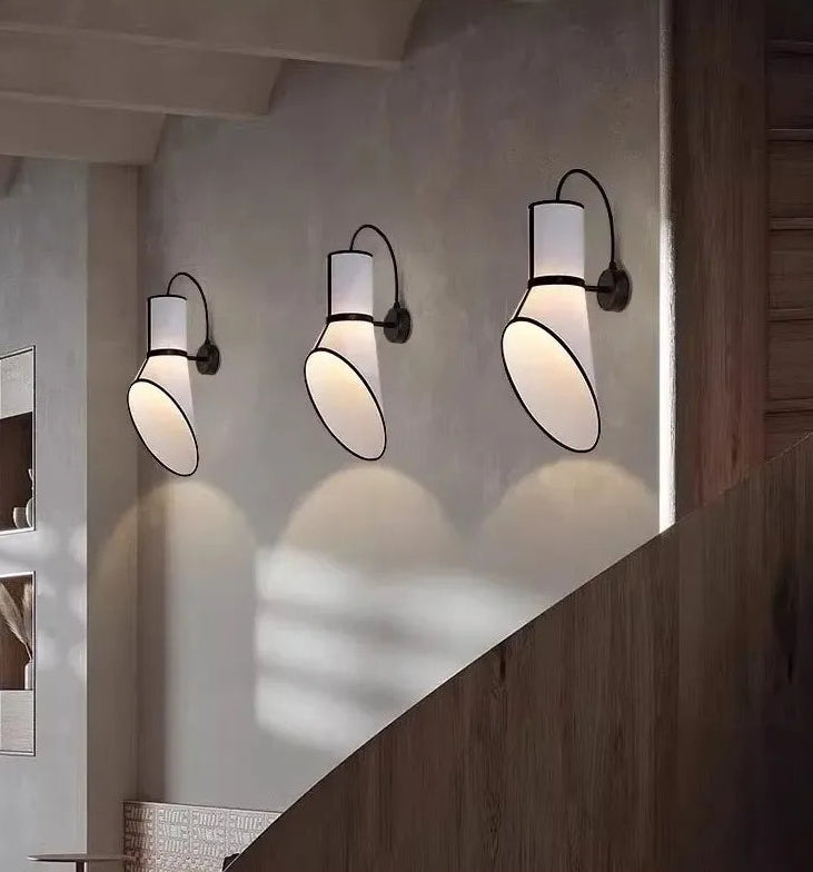 Three wall-mounted lights on a wall with a wooden staircase in the foreground