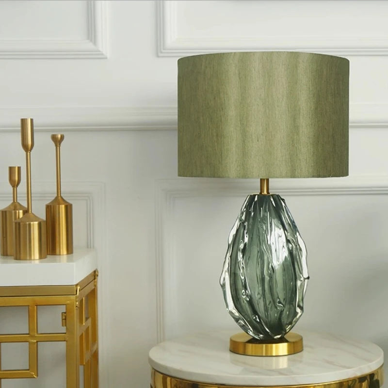 Decorative lamp with green glass base and gold accents on a marble surface.