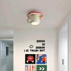 A red and white mushroom-shaped ceiling light with a squirrel accent mounted on a white wall, with colorful artwork below.