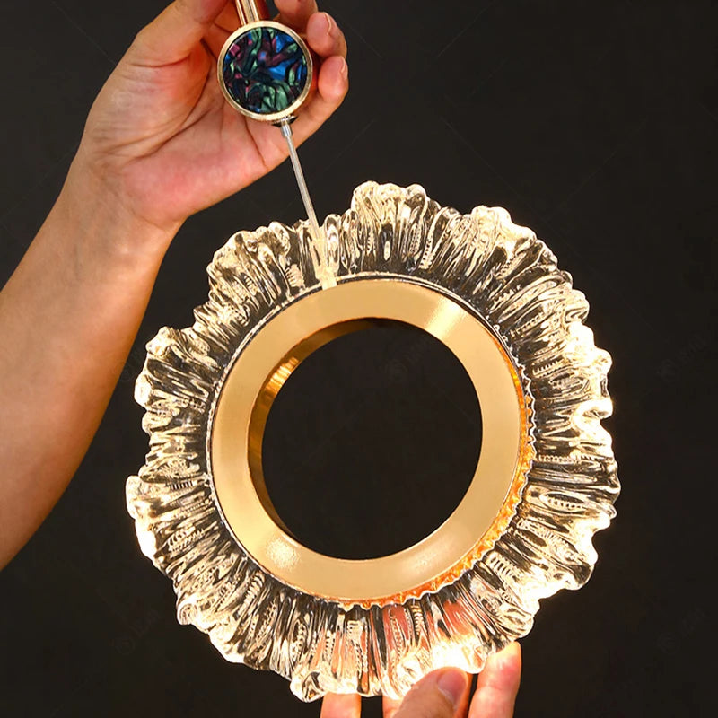 Decorative mirror with gold frame and textured edge held by a hand against a black background
