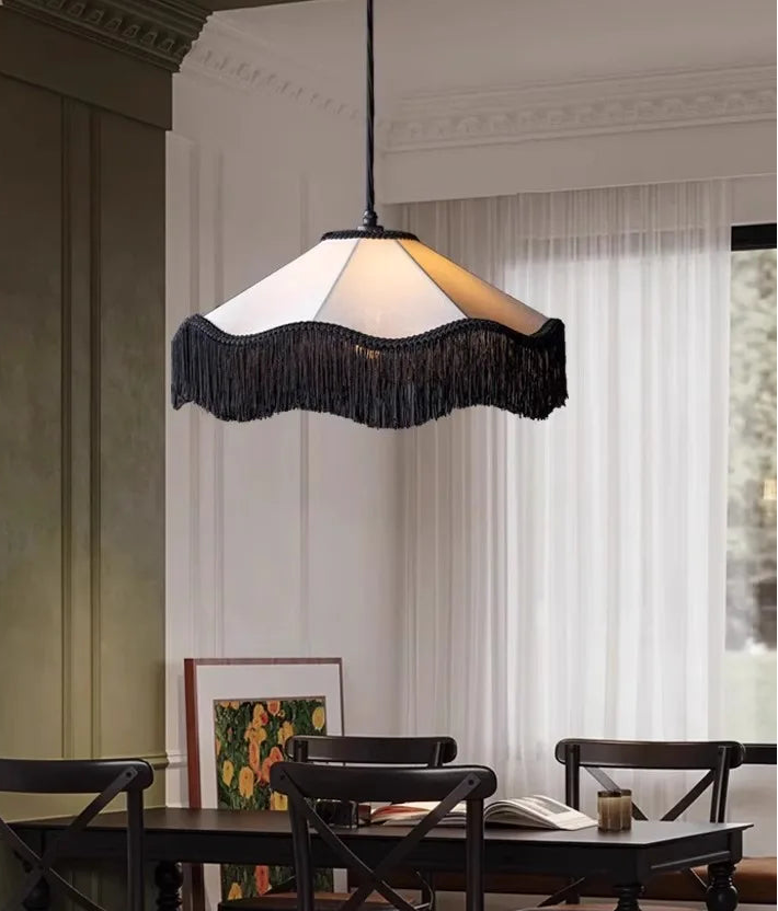 Dining room with a black fringed pendant light hanging above a wooden table.