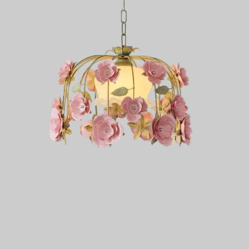 Close-up view of a gold chandelier adorned with pink fabric roses and green leaves.