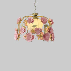 Close-up view of a gold chandelier adorned with pink fabric roses and green leaves.