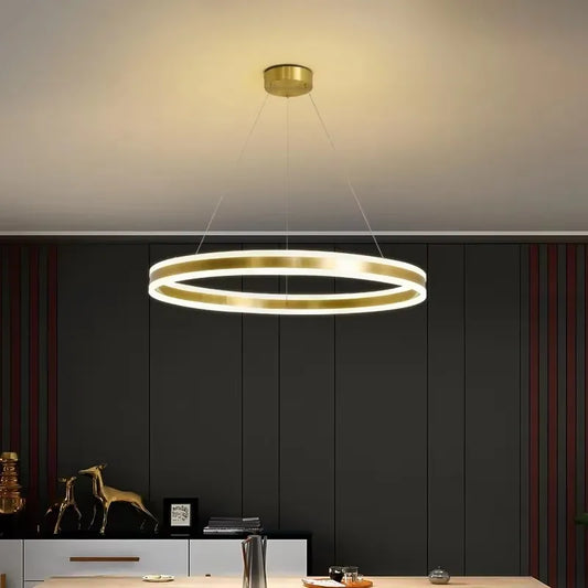 Gold ring pendant light with a polished gold finish, suspended from the ceiling, emitting a warm glow.