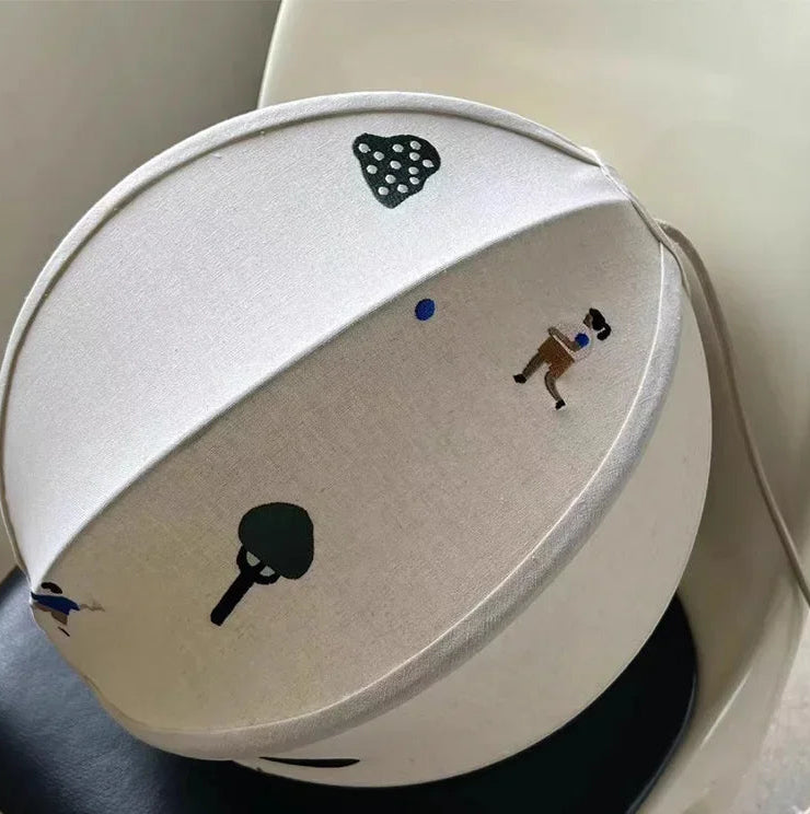 White lampshade with black and brown illustrations on a white background