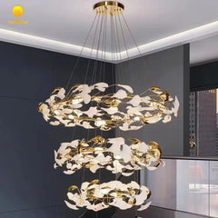 Close-up of a gold ring chandelier with intricate white and gold leaf details, illuminated against a dark background.