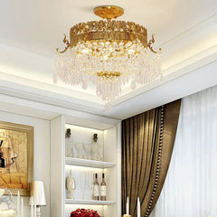 A gold semi-flush crystal ceiling light fixture illuminating a living room with white walls and brown drapes.