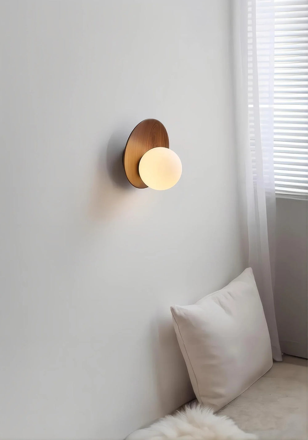 A dimly lit bedroom scene featuring a wood arc wall sconce with a frosted glass globe above a pillow.