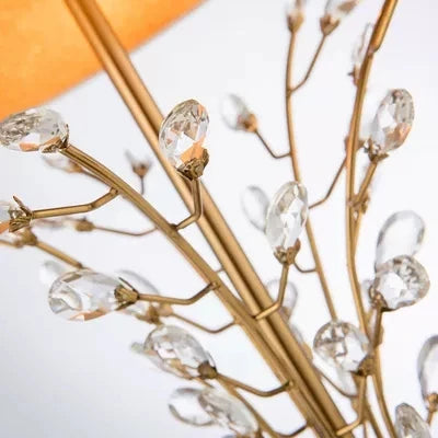 Decorative wall piece with gold branches and clear crystal-like beads on a white background