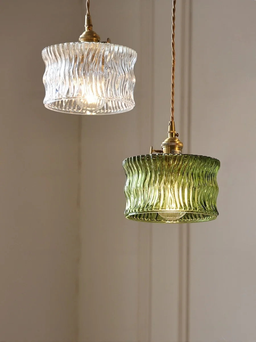 Two pendant lights with ribbed glass shades on a neutral wall.
