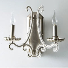 Decorative wall sconce with two candle-style lights on a plain background