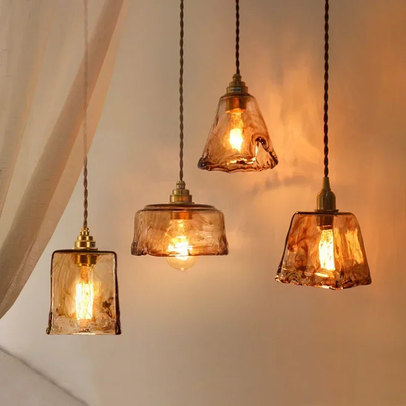 Four vintage-style pendant lights with glass shades on a neutral background