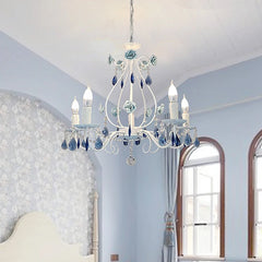 White chandelier with blue floral elements and crystal pendants, installed in a bedroom with blue floral wallpaper and arched windows.