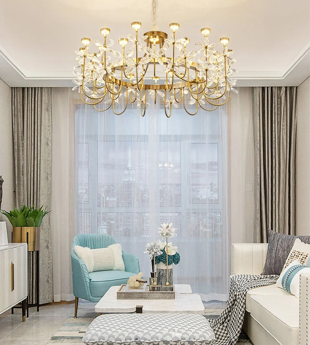 Luxurious living room with a gold chandelier, light blue armchair, and white sofa.