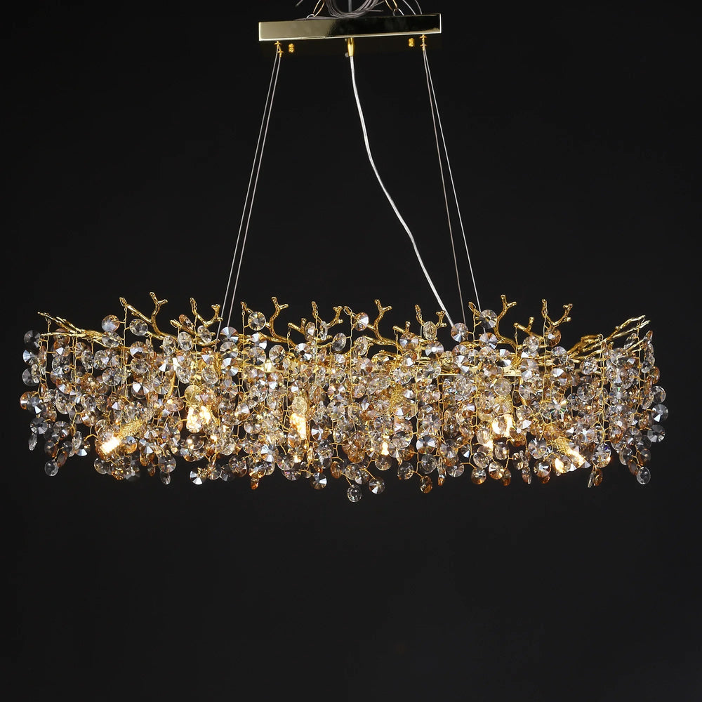 Gold crystal chandelier with a branch-like design and clear faceted crystals against a black background.