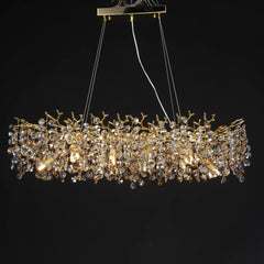 Gold crystal chandelier with a branch-like design and clear faceted crystals against a black background.