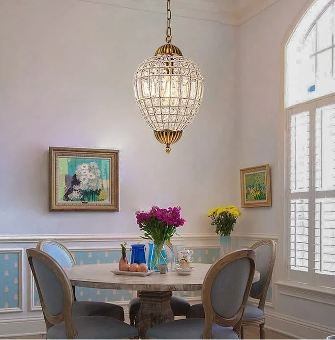 Dining room with a crystal chandelier, table, chairs, and floral arrangements.