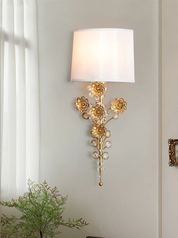 A close-up of a gold floral crystal wall sconce, highlighting the detailed metalwork and crystal accents.