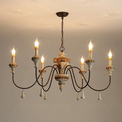 A distressed wood and iron chandelier with six candle-style lights against a plain background.