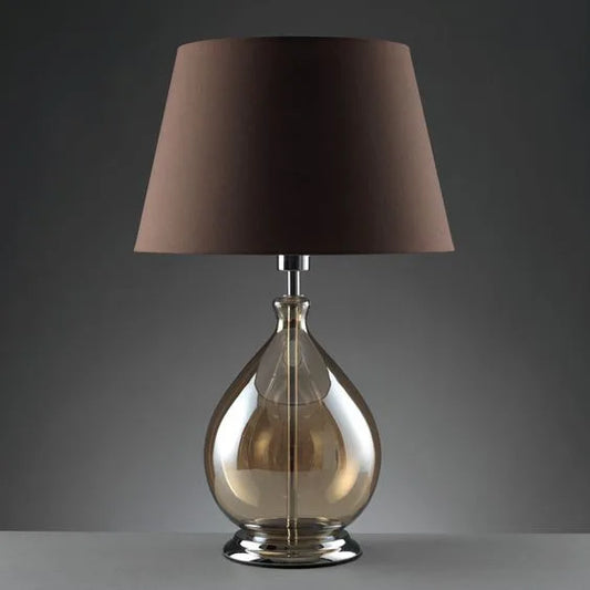 Amber glass table lamp with a dark fabric shade, displayed against a plain grey background.