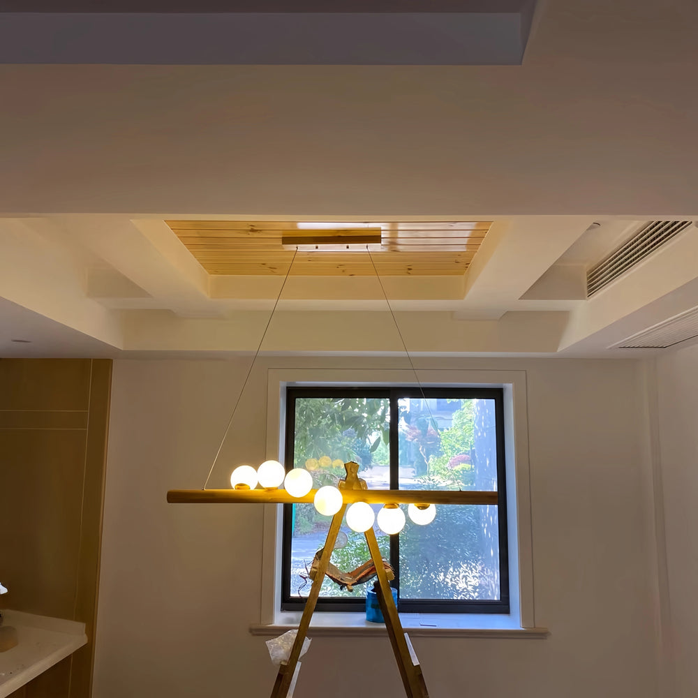 Modern chandelier hanging in a room with a window and ceiling air conditioning unit.