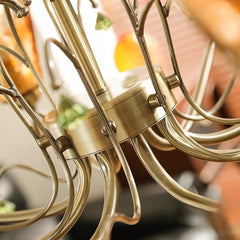 Close-up of the central structure and arms of the bronze chandelier, highlighting the metallic finish and decorative elements.